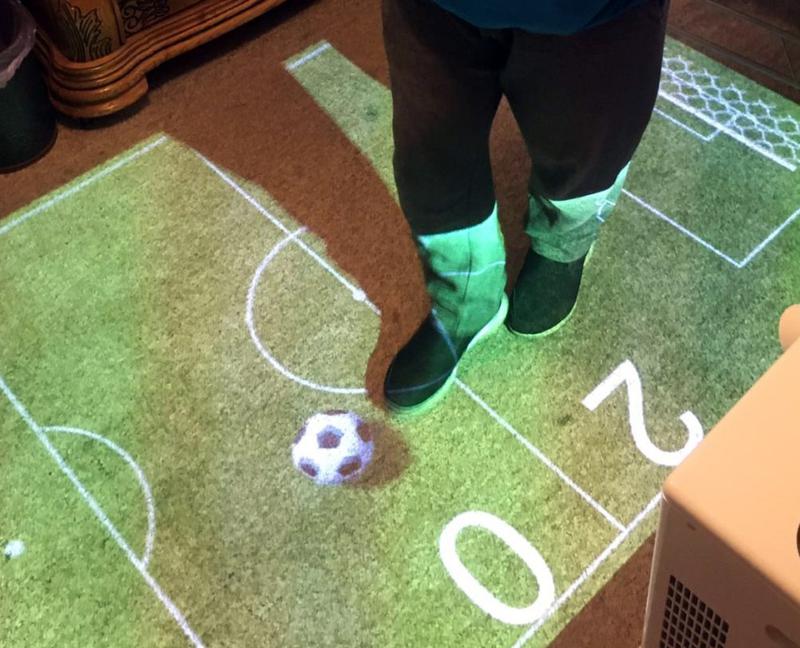Person playing ball game with feet on projected floor image